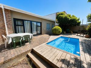 a patio with a table and a swimming pool at Sandy Fingers Apartment in Plettenberg Bay