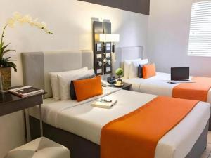a bedroom with two beds with orange and white pillows at Majestic Hotel Manila - Formerly Octagon Mansion Hotel Manila in Manila +261 photos