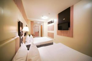 a hotel room with two beds and a flat screen tv at Majestic Hotel Manila - Formerly Octagon Mansion Hotel Manila in Manila