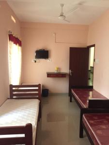 a room with two beds and a tv on the wall at Mega Tourist Home in Guruvāyūr