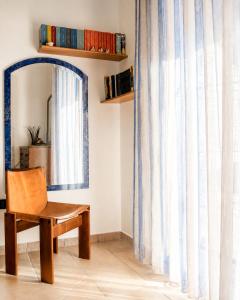 a chair and a mirror in a room at La casa del viaggiatore in Codrongianos