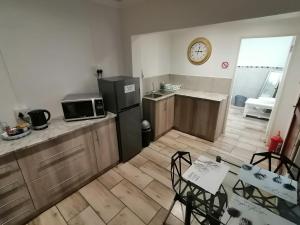 a kitchen with a refrigerator and a table and a clock at Sleep@161 Benade Drive in Bloemfontein