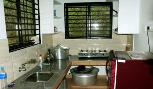 a kitchen with a sink and a stove top oven at Villa Abu Sulthan - Garden Farm House in Kūmudi