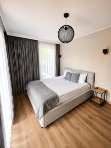 a bedroom with a large bed and a pendant light at Apartamenty Lipowa in Puck