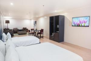 a bedroom with two beds and a living room at Green Sun Hotel in Manila