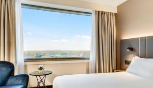 a hotel room with a bed and a large window at NH Brussels Airport in Diegem