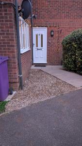 a brick building with a white door and a sidewalk at 70's Inspired 1 Bed flat in Knebworth