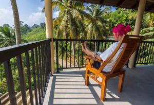a woman sitting in a chair on a porch at Rainforest Hide View in Deniyaya