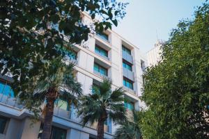 a white building with palm trees in front of it at Heykel Suites Otel in Konak