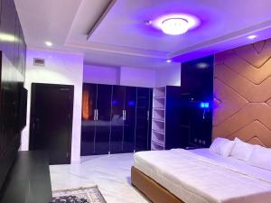 a bedroom with a bed and a purple lighting at Laycon hotel and suites in Ikuata