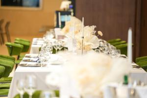 a long table with white tables and green chairs at UNA Hotels La Martella Matera in Matera