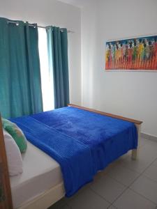 a bedroom with a bed with blue sheets and a window at Fumbatown's Finest in Mchamba Wima