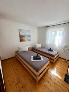two beds in a room with wooden floors at Apartment Dalmatera in Rogoznica