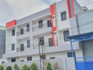 a white and red building with plants in front of it at Mahkota Residence Mitra RedDoorz in Karawang
