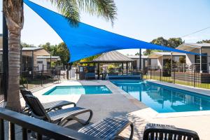 a pool with two chairs and a blue umbrella over it at Geelong Holiday Park in Geelong
