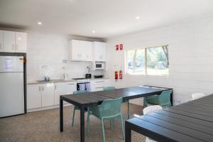 a kitchen with a table and chairs and a refrigerator at Geelong Holiday Park in Geelong