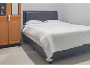 a bed with white sheets and pillows in a room at Mahkota Residence Mitra RedDoorz in Karawang