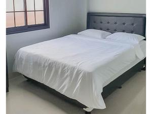 a bed with a white comforter on top of it at Mahkota Residence Mitra RedDoorz in Karawang +6 photos