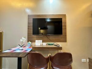 a table with two chairs and a television on a wall at Cozy Modern Loft Studio in Cubao in Manila
