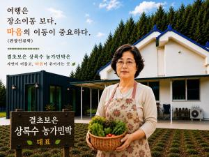 a woman holding a basket of vegetables in front of a house at 상록수 sangroksu in Boeun