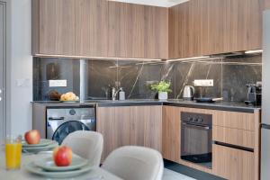 a kitchen with wooden cabinets and a table with chairs at Oasis Luxury Residence B101 - Pool View in Xylophaghou