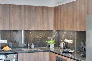 a kitchen with wooden cabinets and a counter top at Oasis Luxury Residence B101 - Pool View in Xylophaghou