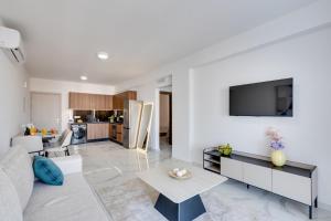 a living room with a white couch and a table at Oasis Luxury Residence B101 - Pool View in Xylophaghou