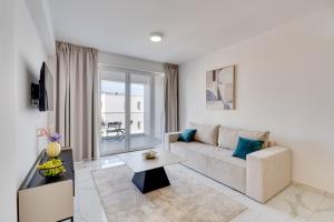 a living room with a couch and a table at Oasis Luxury Residence B101 - Pool View in Xylophaghou +10 photos