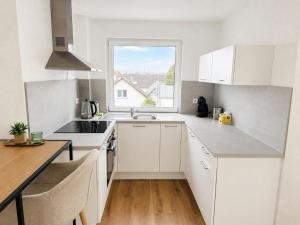 a kitchen with white cabinets and a window at Seven Days Home in Künzelsau