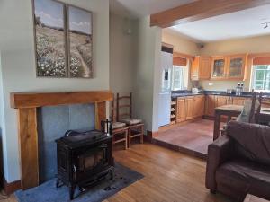 a living room with a fireplace and a kitchen at Lawnside Retreat in Mullinavat