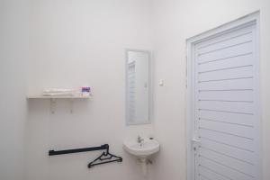 a white bathroom with a sink and a mirror at Urbanview keTemon Hotel & Resto YIA by RedDoorz in Yogyakarta +74 photos