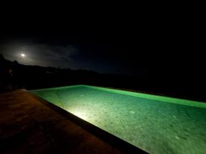 a swimming pool at night with the moon in the background at Aadya Tea Bungalows by Aahaasa in Hatton