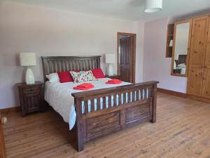 a bedroom with a large wooden bed with red pillows at Lawnside Retreat in Mullinavat