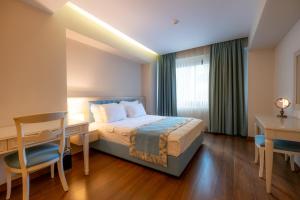 a hotel room with a bed and a desk and a table and chairs at Heykel Suites Otel in Konak