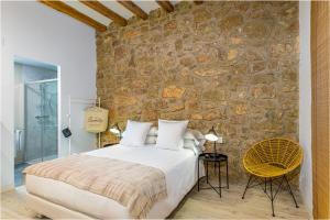 a bedroom with a bed and a stone wall at La Casa del Miracle, hostal in Balaguer