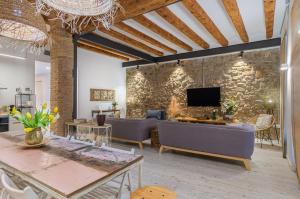 a living room with couches and a tv on a stone wall at La Casa del Miracle, hostal in Balaguer
