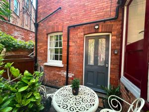 a brick house with a blue door and a table with a plant at Mews Apartments in Lincoln