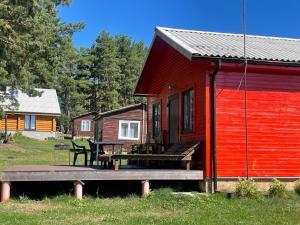 a red cabin with a bench and a table at Rāznas ezera namiņš D1 ar elektrisko apkuri in Ragi