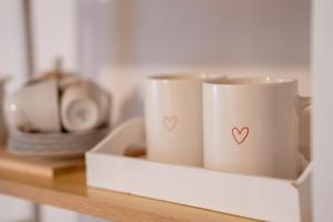 two mugs with hearts on them sitting on a shelf at A Cuor Leggero Home in Viterbo +13 photos