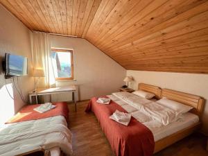 two beds in a room with a wooden ceiling at Chabarukhi Gudauri Truso in Gudauri