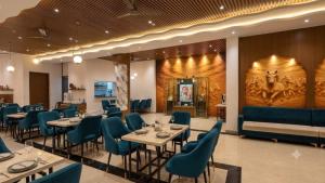 a dining room with tables and blue chairs at Hotel De - Grand Villa Near Delhi IGI Airport in New Delhi