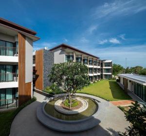 a courtyard of an apartment building with a tree in a fountain at i Tara Private in Ban Laem Phak Bia (1)