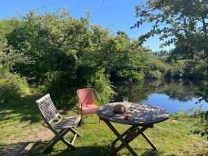 a table and two chairs sitting next to a lake at Tresahor Studio with sauna in Falmouth