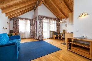 a living room with a blue couch and a table at Hotel Vajolet in San Cassiano