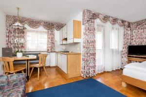a living room with a bed and a kitchen with a table at Hotel Vajolet in San Cassiano