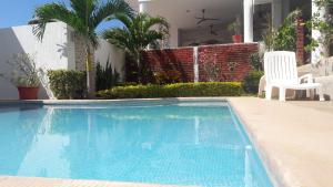 a swimming pool with two white chairs next to a house at Hotel Casa Chacala in Chacala