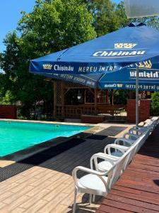 a swimming pool with a blue umbrella and white chairs at Cazare-LaBadeaMircea in Soroca