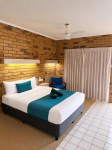 una camera da letto con un grande letto con cuscini blu di Boulder Opal Motor Inn a Winton Altre 5 foto