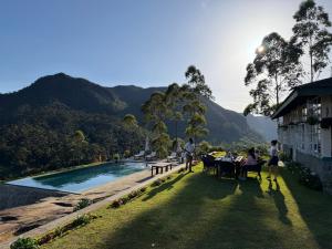 a group of people sitting around a table by a pool at Aadya Tea Bungalows by Aahaasa in Hatton