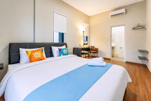 a bedroom with a large bed with orange and blue pillows at Sans Stay Bintaro in Pondoklang